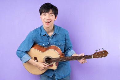 portrait of asian man in blue shirt posing on purple background