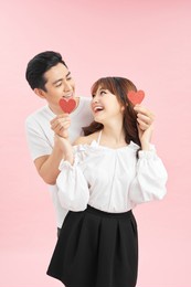 portrait of his he her she nice attractive lovely funny funky cheerful cheery glad couple holding in hands small little hearts isolated on bright pink background