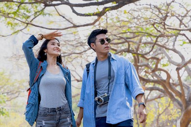 young asian couple hiking outdoors in forest. active young asian man and woman trekking in forest