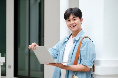 focused young male college student working on a laptop on some stairs on campus preparing for an exam.