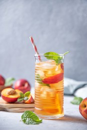 cool peach tea with mint and ice in a glass on a blue background. vertical orientation.  front view and copy space  image