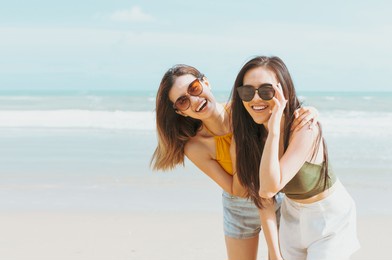 two asian women friends in summer casual clothes take a photo together at the beach on vacation in tropical country. young beautiful female joy in the beach on a sunny day