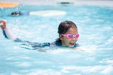 asian child girl playing water and swimming in the swimming pool with her friend with fun. summer activity and childhood lifestyle concept.