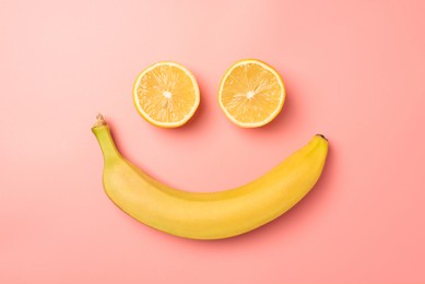 top view photo of smiling face made from two lemon halves and banana on isolated pastel pink background