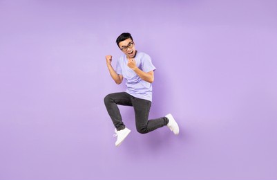 portrait of a jumping asian man, isolated on purple background
