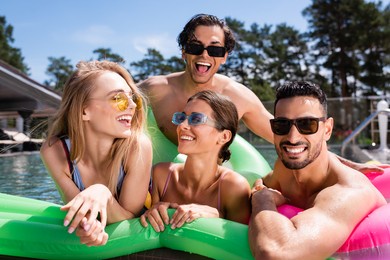 cheerful multiethnic friends having fun on inflatable mattress in swimming pool