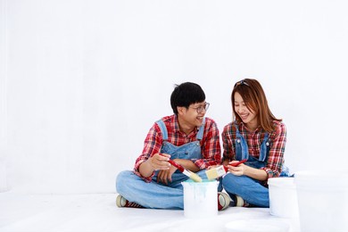 portrait young asian couple in yom-bear and plaids shirts painting a new color the room renovation concept 