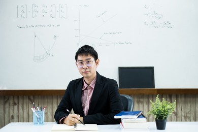an asian male teacher at the university is preparing lessons to teach in the classroom.
