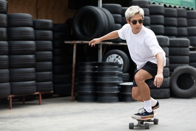 young man skater riding on skateboard at tires automobile store