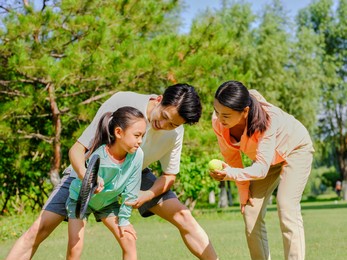 happy family of three playing tennis in the park high quality photo