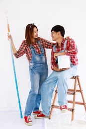 portrait young asian couple in yom-bear and plaids shirts painting a new color the room renovation concept 