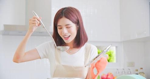 portrait of beautiful young asian woman cooking soup with smiling in light white interior style kitchen
