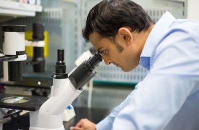 closeup portrait, young scientist looking into microscope. isolated lab background. research and development.