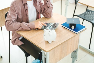 teenage boy with savings for education and calculator in classroom