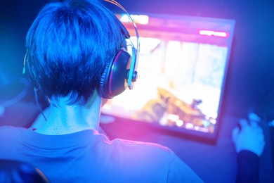 blurred background professional gamer playing tournaments online games computer with headphones, red and blue.