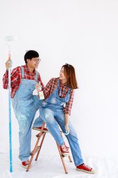 portrait young asian couple in yom-bear and plaids shirts painting a new color the room renovation concept 