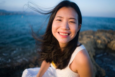 young happy and beautiful asian woman by the sea - attractive korean girl cheerful enjoying relaxed summer holidays at tropical island in travel and lifestyle concept