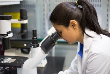 closeup portrait, young scientist looking into microscope. isolated lab background. research and development.