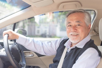 portrait of smiling asian senior man , old man , elderly man driving a car 