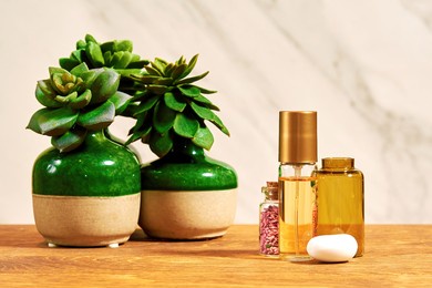shiny golden perfume bottle with a small flask with pink petals and succulents. makeup and beauty shop desk backgrounds