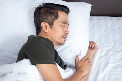 asian man sleeping comfortably on a white bed