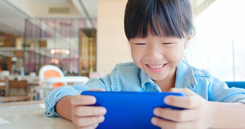 asian cute girl play mobile game happily in the restaurant