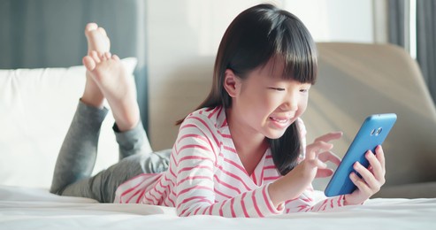 asian cute girl use smart phone and lay on the bed at home