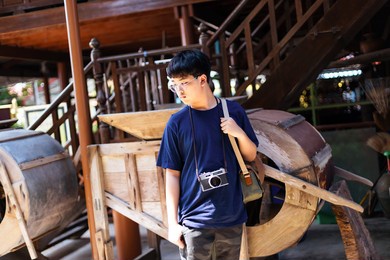 asian teenage boys holds a vintage film camera and take pictures at tourist attractions.