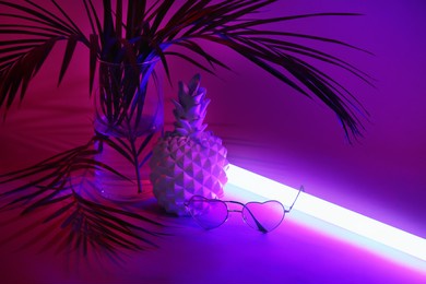 ceramic pineapple with sunglasses and tropical leaf on dark color background