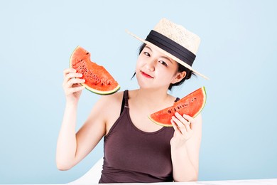 smiling woman wearing a straw hat and holding watermelon in both hands