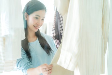 beautiful asian housewife arrange and choose cloth for dress with morning light in walkon closet