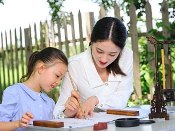 happy mother and daughter write calligraphy outdoors high quality photo
