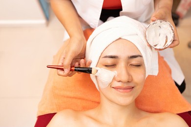 young woman with facial mask at beauty spa salon