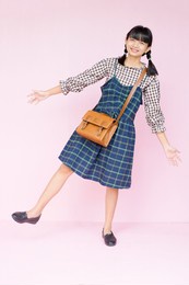 portrait student youn girl with smile hold brown bag on pink background.