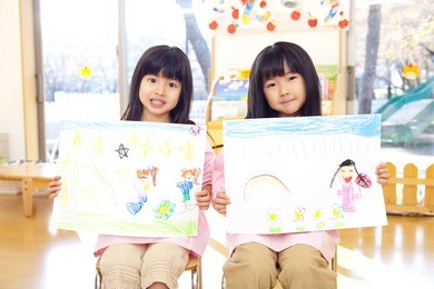 two smiling kindergarten girls with a picture