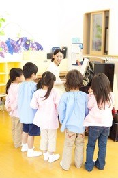 kindergarten children singing along to the piano of kindergarten teachers