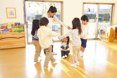 children and a nursery teacher dancing in a circle