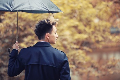 autumn park in rainy weather and a young man with an umbrella
