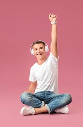 teenage boy listening to music on color background