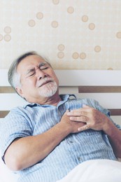 senior asian man  suffering from bad pain in his chest heart attack at home - senior heart disease concept