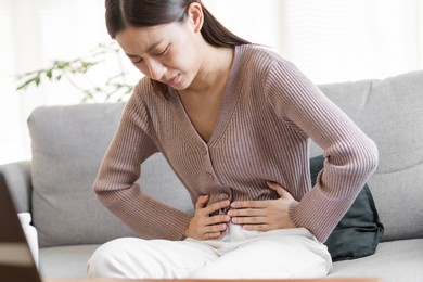 flatulence asian young woman, girl hand in stomach ache, suffer from food poisoning, abdominal pain and colon problem, gastritis or diarrhoea. patient belly, abdomen or inflammation, concept.