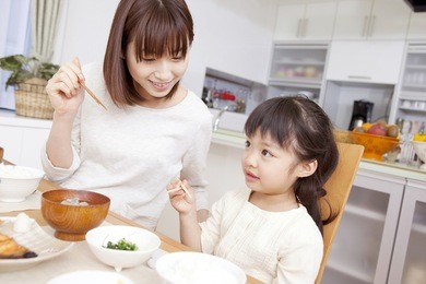 a mother teaching how to use chopsticks with her daughter