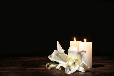 candles with lily flowers on table against dark background