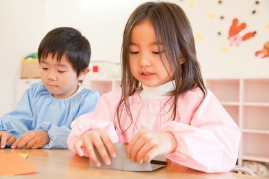 kindergartener making a folded-paper
