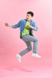 vertical image of happy man jumping in studio  over pink background