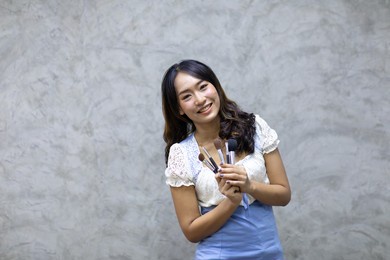 portrait of make up artist woman with makeup brushes isolated on white wall background