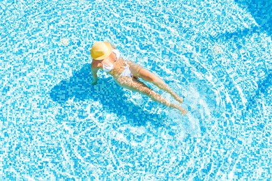 young alone beautiful sports woman in bikini and hat is swimming in swimming pool. aerial drone view from above. tropical summer vacation