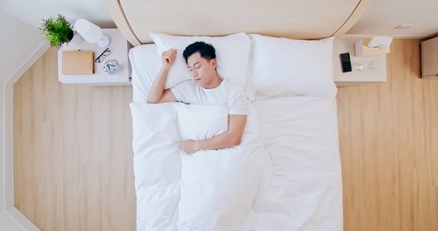 overhead view of young asian man sleeping well and relaxing in the morning