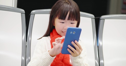 asian cute girl use smart phone outdoor with scarf and sweater on bus