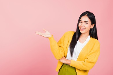 asian happy portrait beautiful cute young woman smile standing presenting product holding something on palm away side, studio shot isolated on pink background with copy space, female show hand gesture